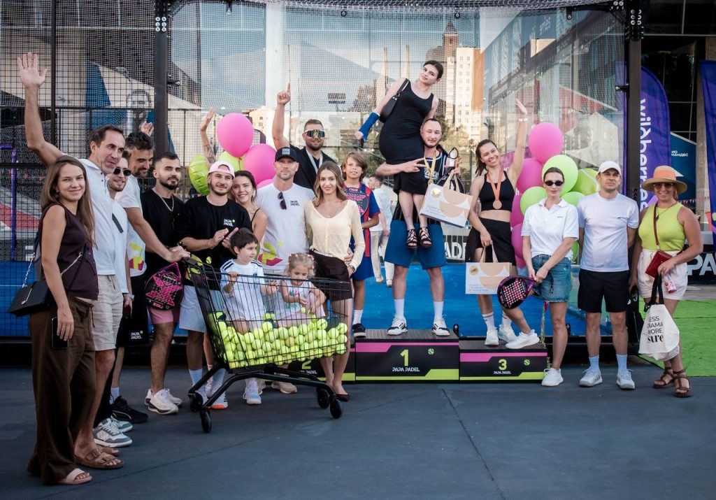 Group of padel players posing with rackets at an outdoor club court