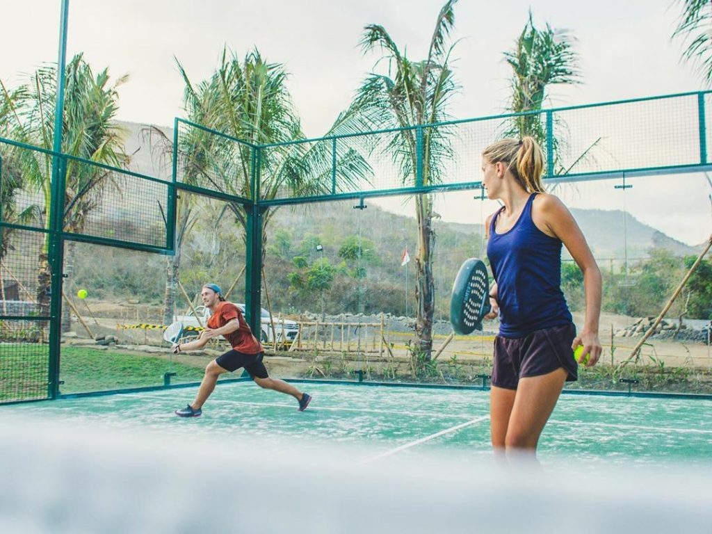 Female padel player on a blue court under a sunny sky