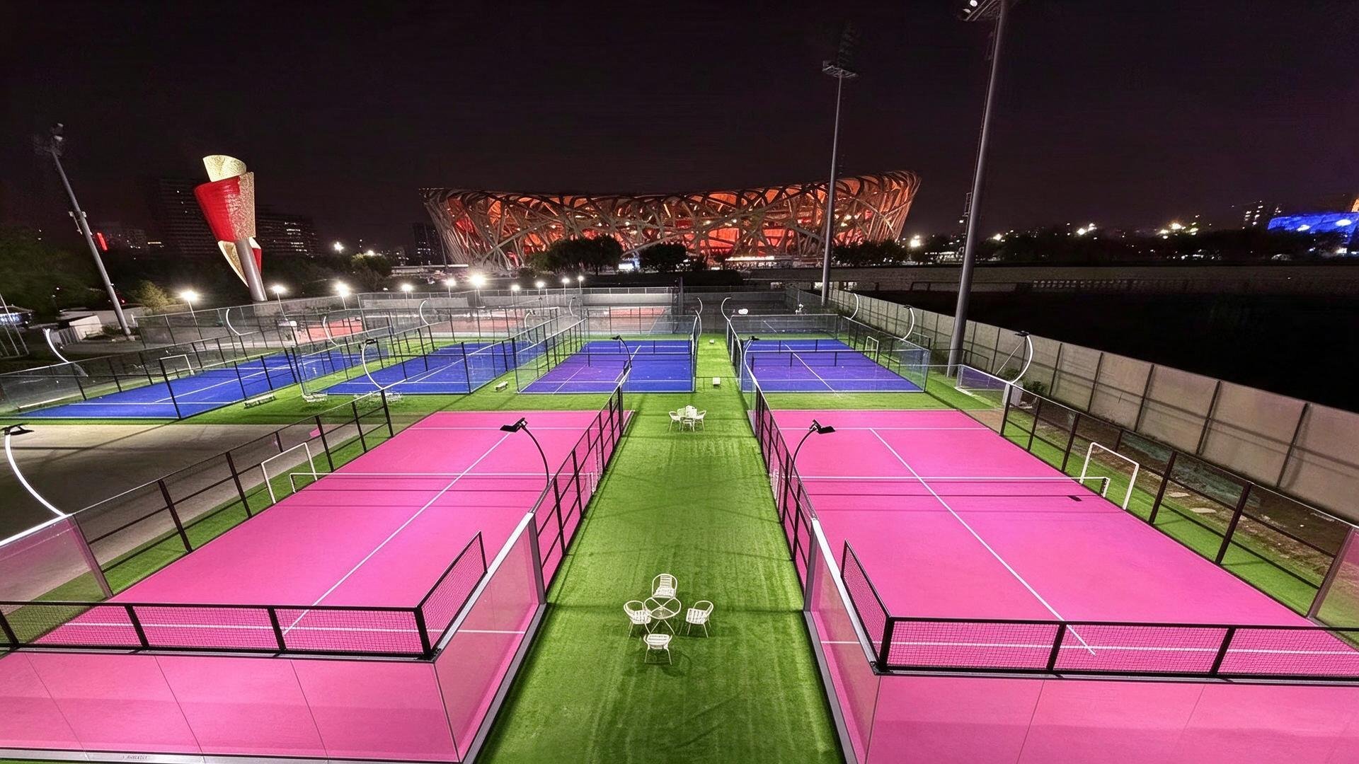 Aerial view of a panoramic padel court complex with multiple courts lit at night