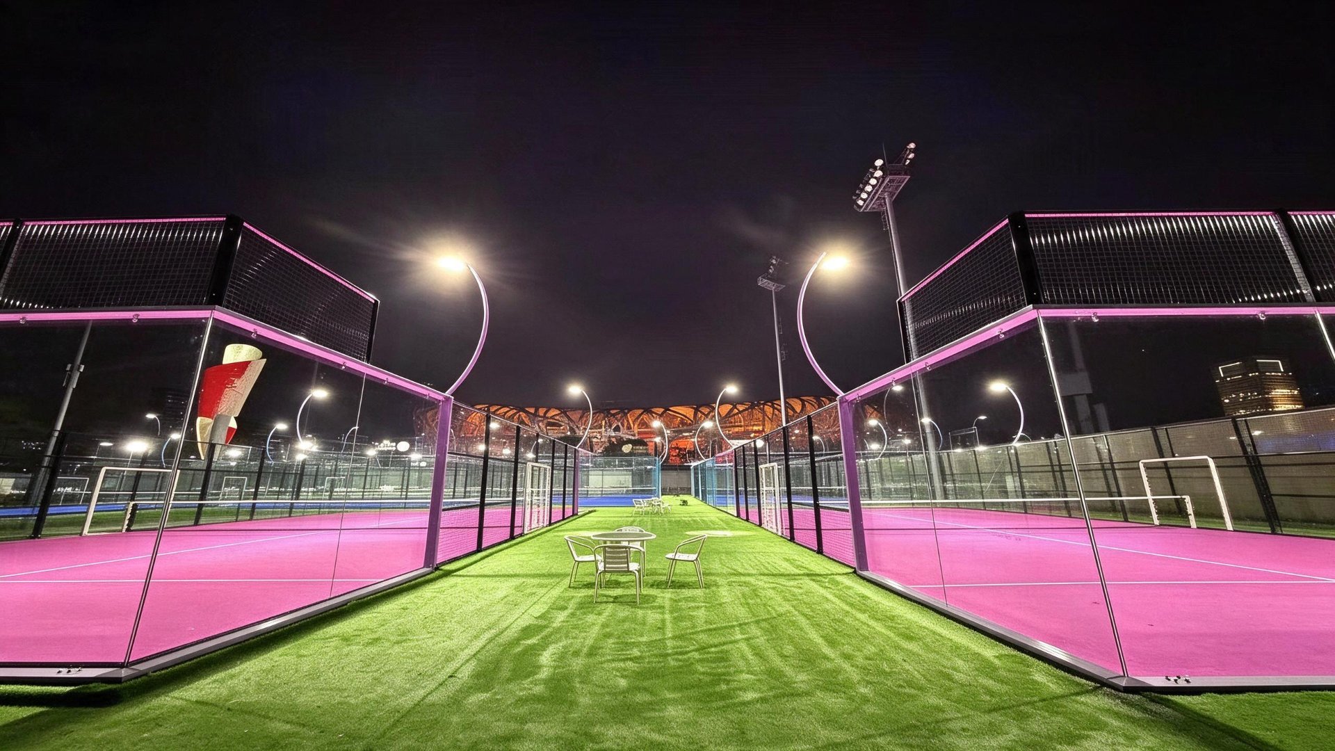 Glass-walled panoramic padel court walkway between courts at night