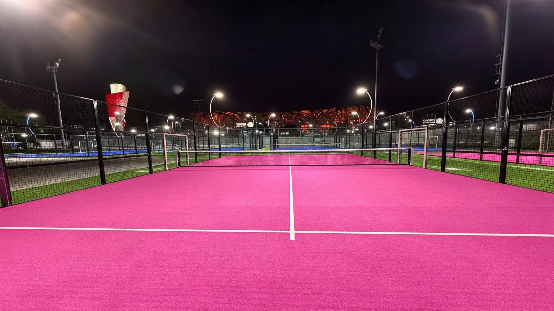 Illuminated panoramic padel court surface with centre net at night