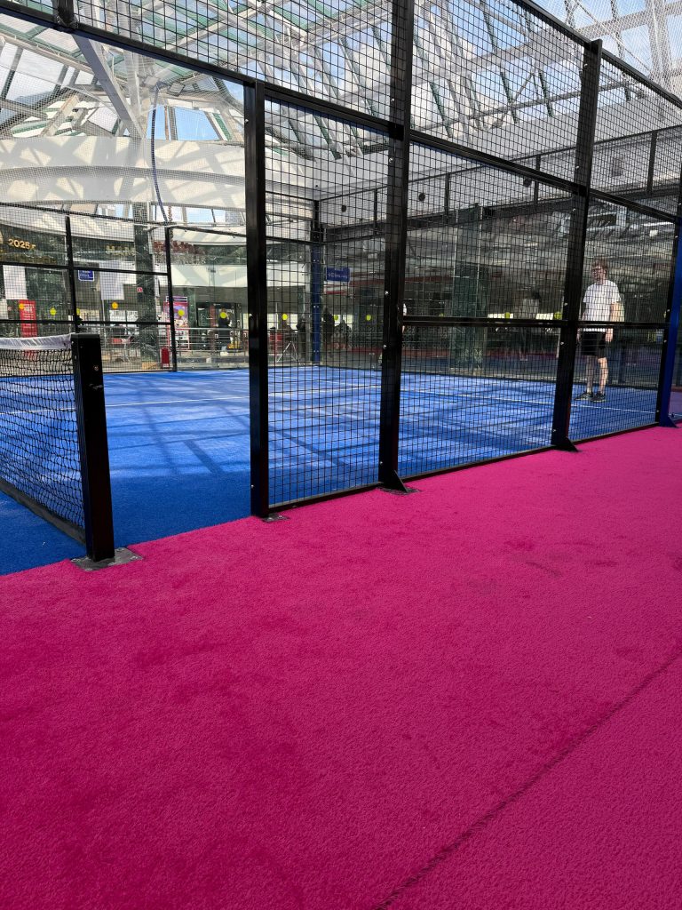 Pink padel court surface with artificial turf and white court lines