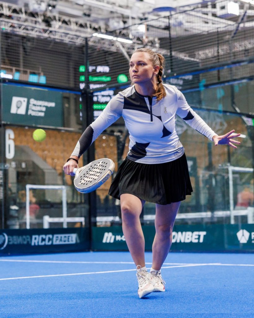 A female player hitting a forehand during an indoor padel match
