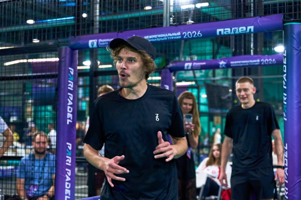 A coach explaining padel court options to a group of players