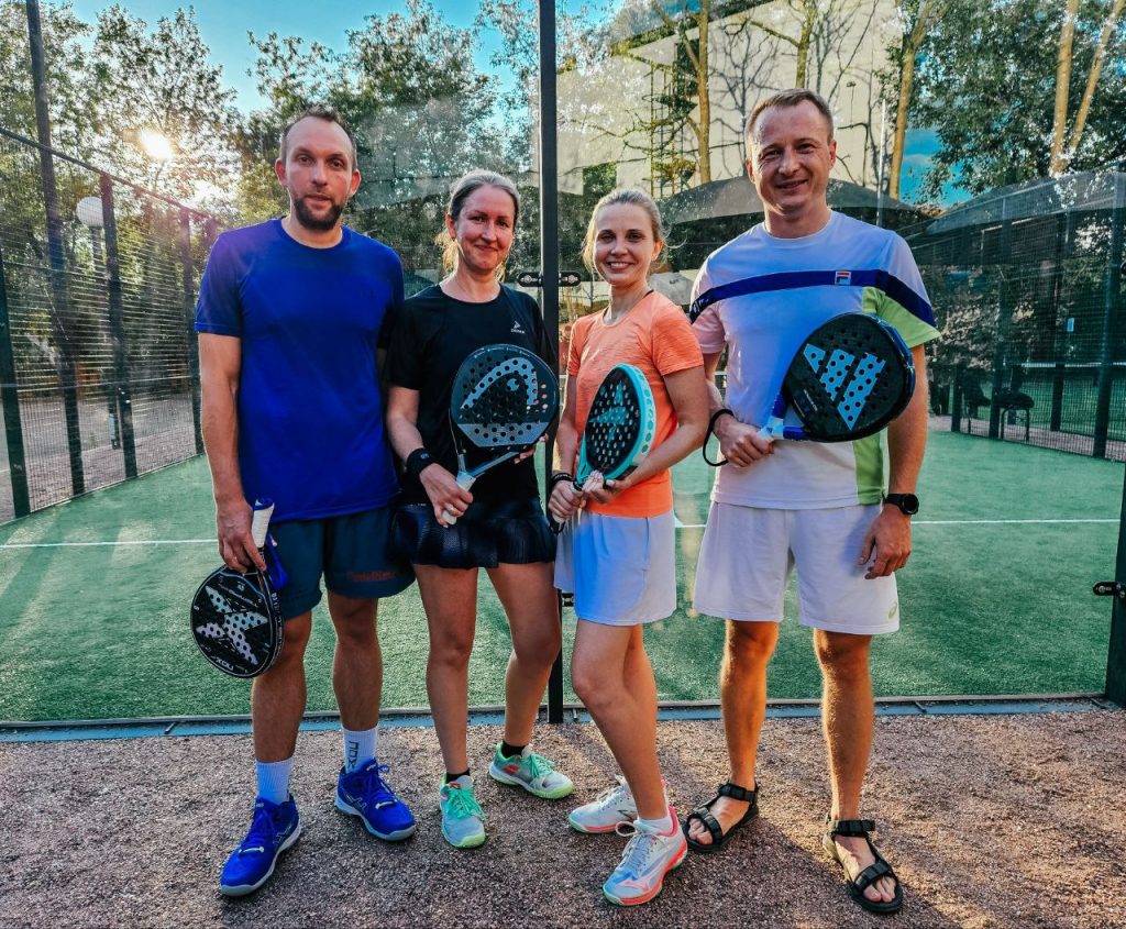 Four padel players posing with their rackets on a green court