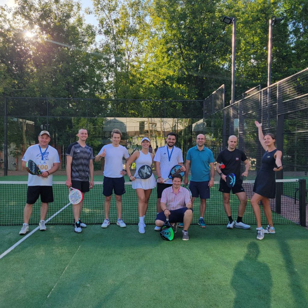 Players posing on an outdoor padel court at sunset