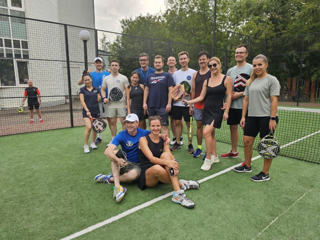 Club members posing with padel rackets on a green padel court
