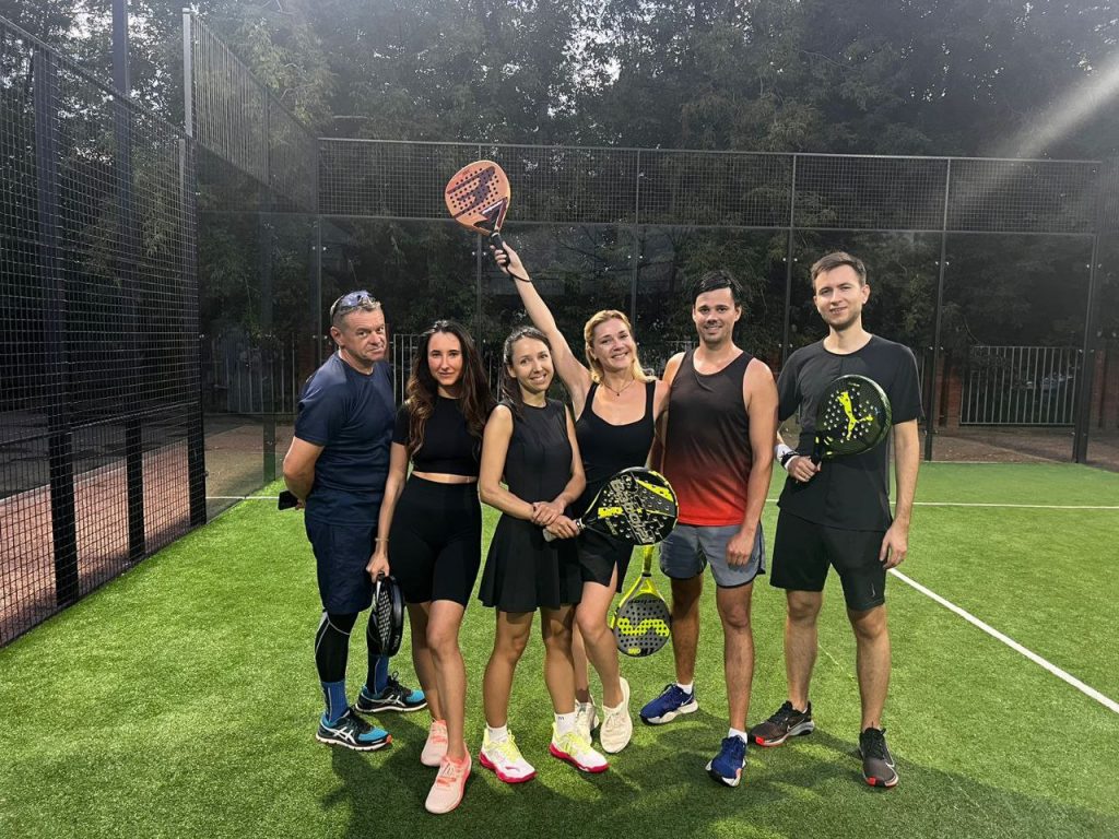 A group of players celebrating on a padel court with rackets raised